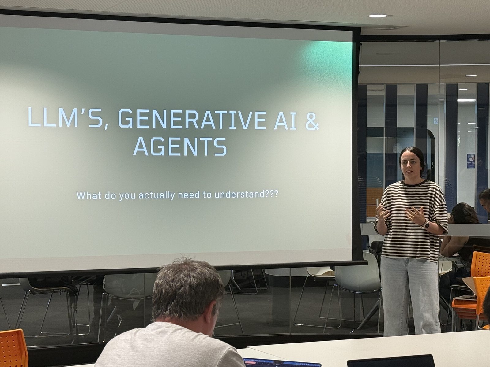 A presenter talking through a slide on LLMs, generative AI and agents to a full room